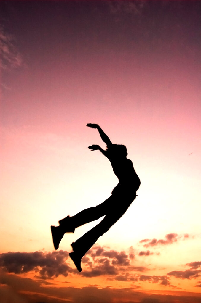 Femme qui saute devant un coucher de soleil